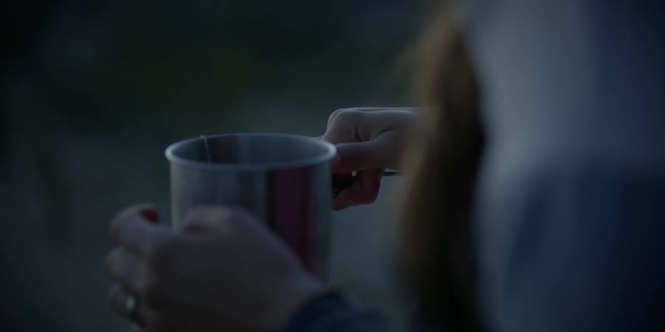 Woman holds a steaming mug of tea and taps her fingers on the mug