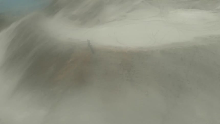 An aerial view of a hiker walking on a sandy ridge in the wilderness