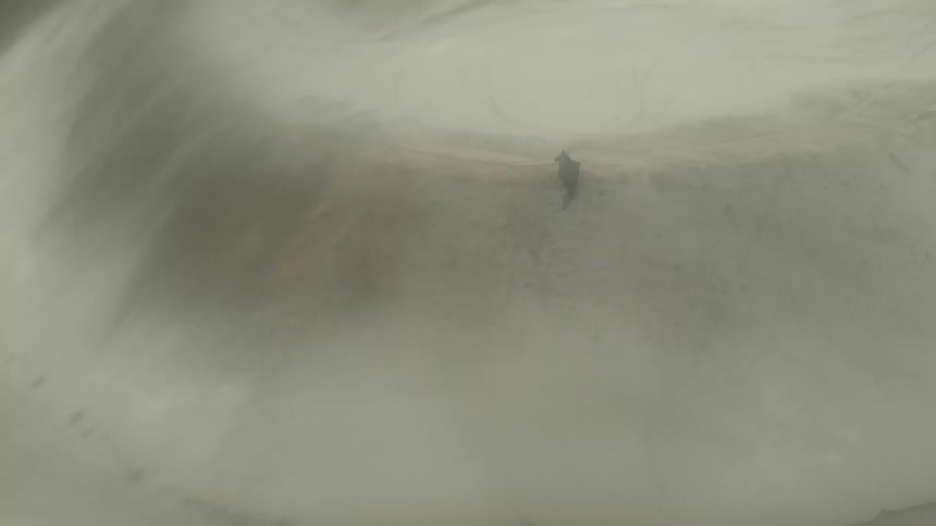 A person swirls their cloak while standing on top of a sand dune