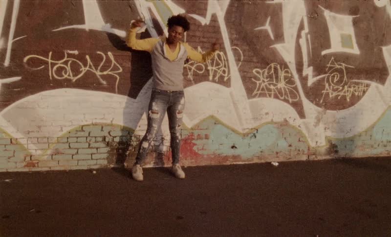 A man standing in front of a wall with graffiti