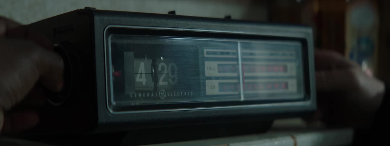 A person twists both knobs of an analogue alarm clock radio