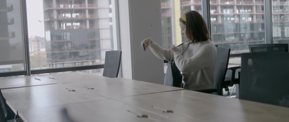 Young woman sits down at a table and takes her laptop out of her bag