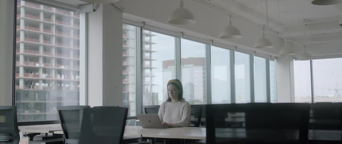 A female working on a laptop at a desk in an otherwise empty office