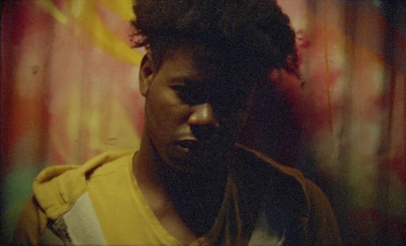 A black young male standing near a painted fence