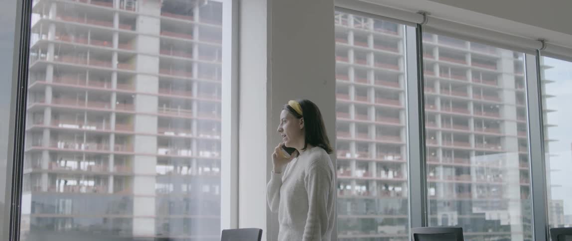 A woman talks on a cell phone while looking out a window