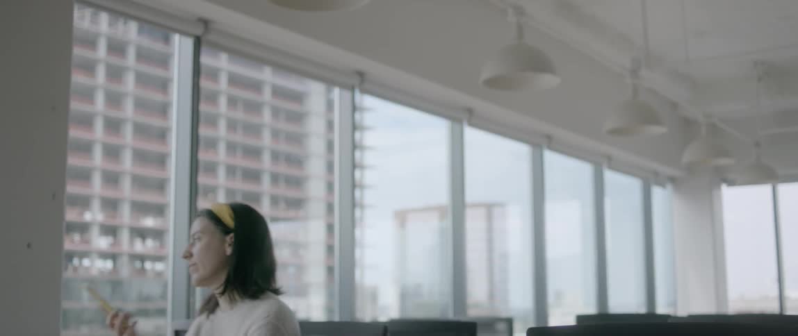 A woman in an office standing up and talking on her smartphone
