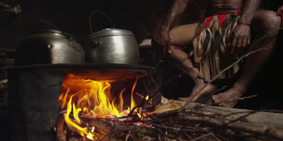 Metal pots cook over an outdoor fire