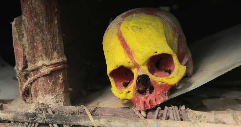 A skull painted yellow and red sits on a hut shelf