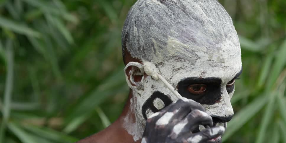 Tribal man applying makeup