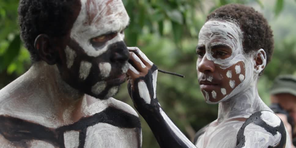 Man painting tribal paint on another man