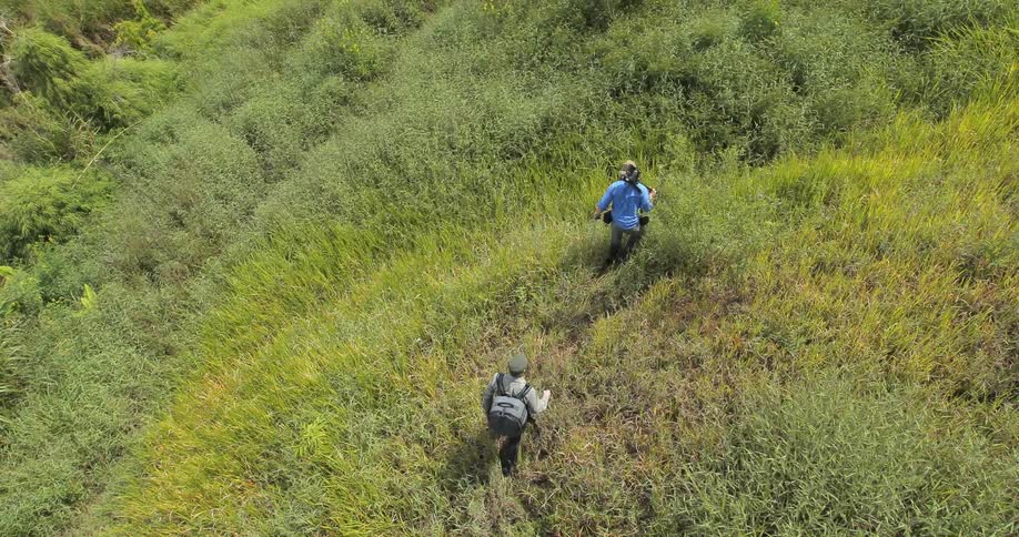 Two people hike over a grassy field