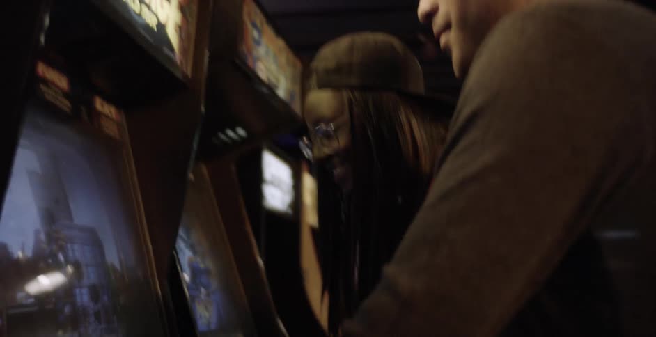 Two people play a rampage arcade game while laughing and smiling
