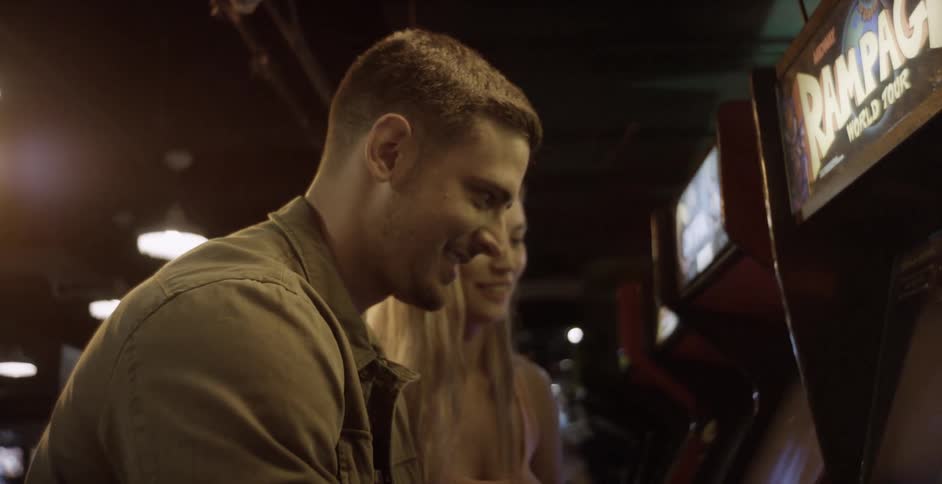 A man and woman laugh and talk while playing a video game