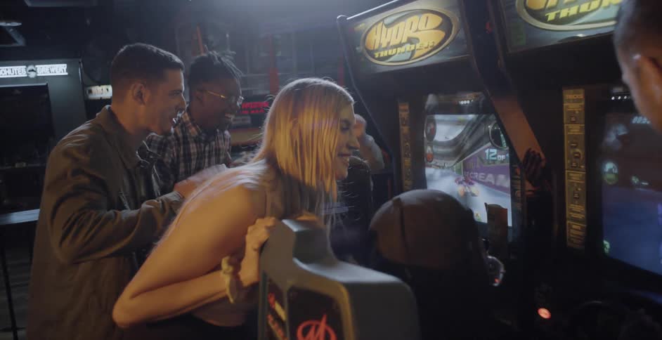 Multiple people playing a racing game at an arcade