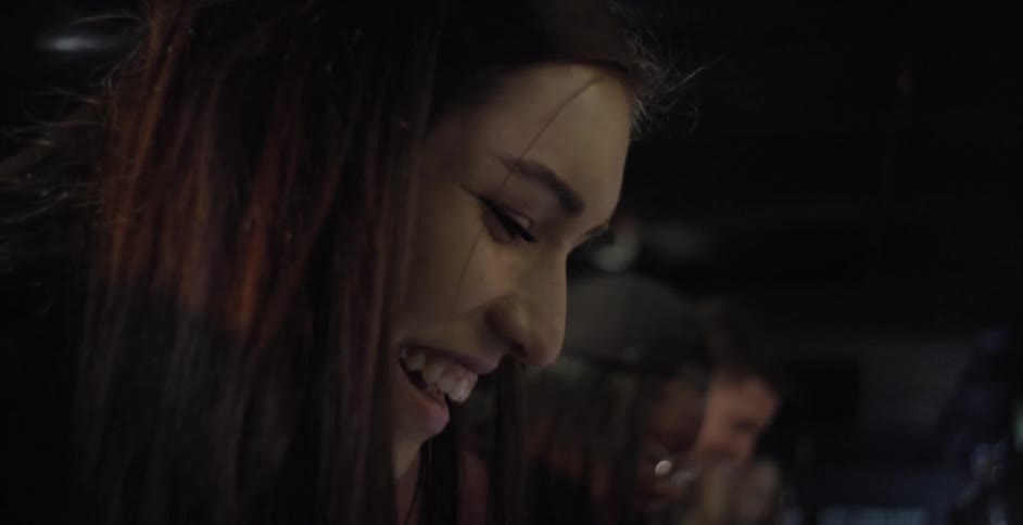 A row of people playing arcade games while laughing and smiling