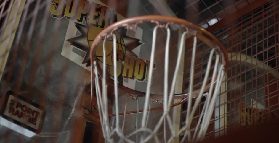 A basketball bounces and then spins inside a net