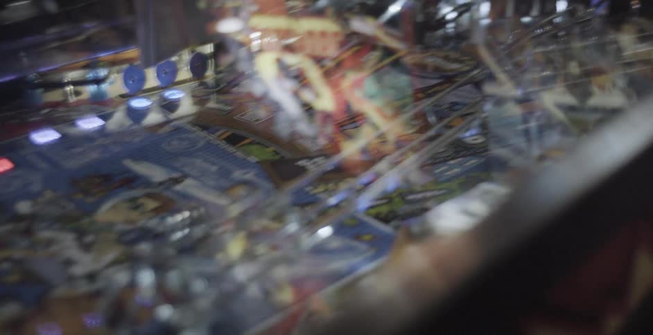 A ball rockets around a pinball machine which contains flashing lights