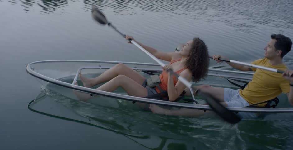 Man and woman canoe across the lake at dusk