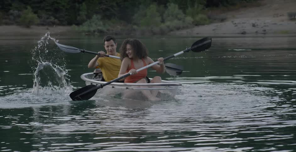 A male and female on a boat rowing on a river