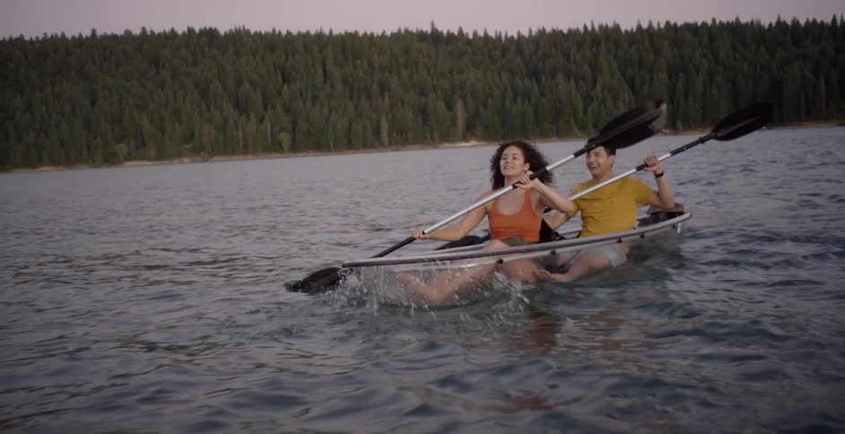 A man and a woman paddle a boat across a lake