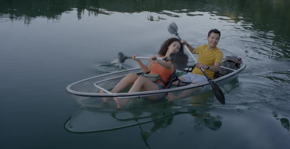 A female and male in a boat rowing on a river