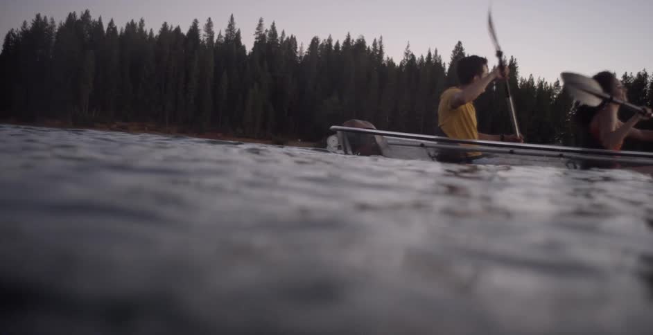 A couple paddle a boat across a lake
