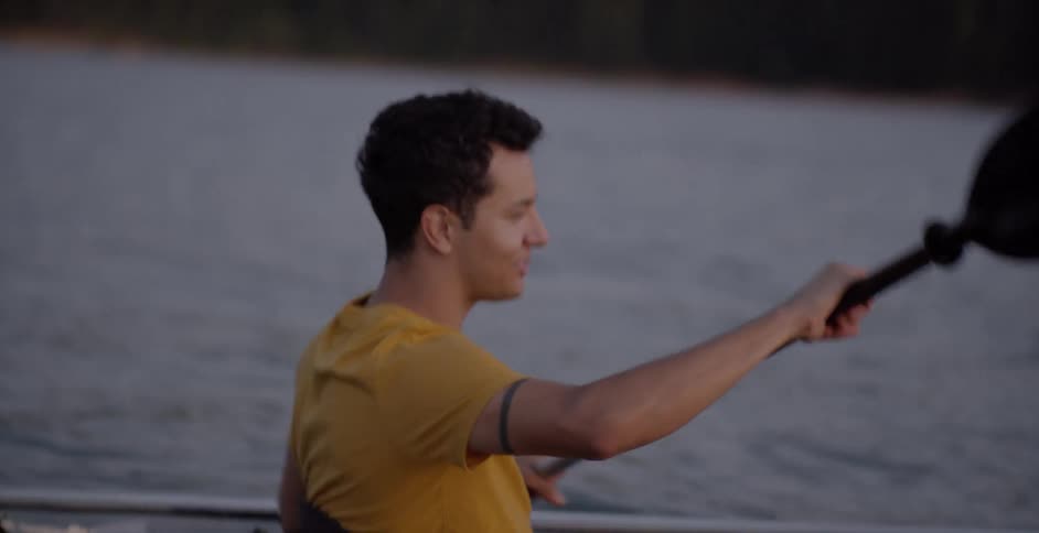 A man talks to a woman while he paddles in a boat