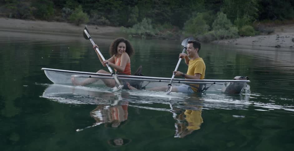 Man and woman row in a clear canoe