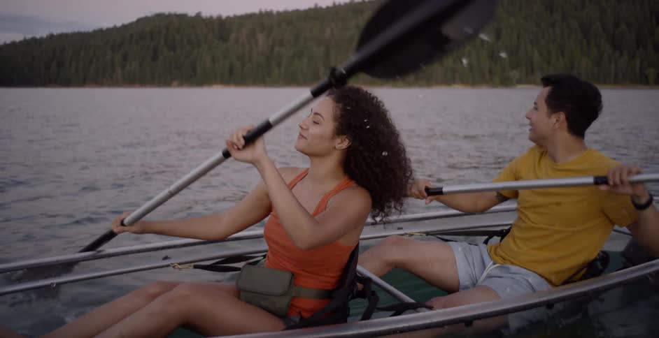 Woman and man canoe across the lake at sunset