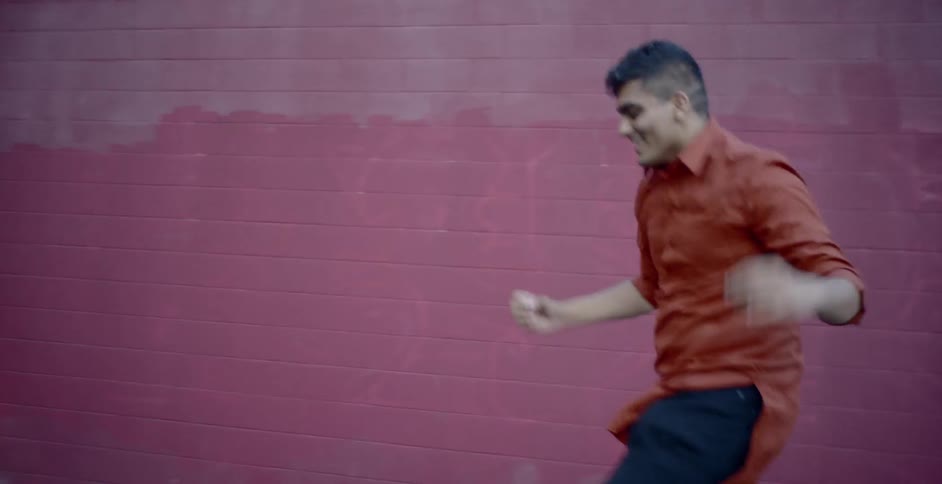 A man performs a contemporary dance outside in an empty lot