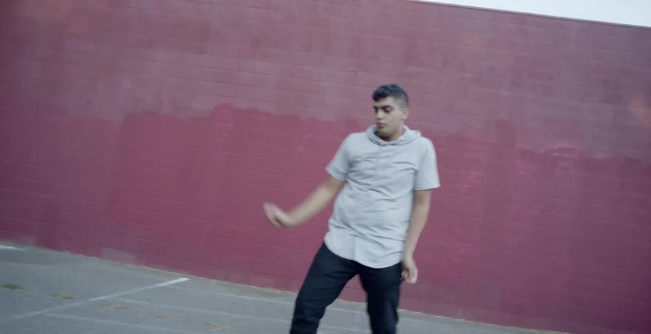 A man dancing in a shaded area of a car park