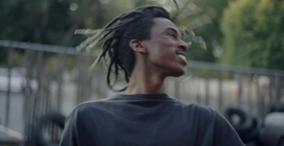 A young blank male shaking his head full of dreadlocks outside