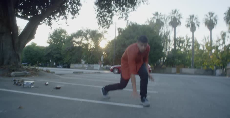 A man is dancing in a dirty parking lot by himself