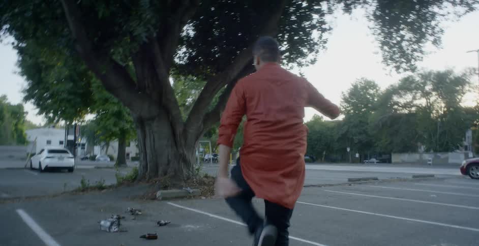 A hispanic teenager in a red shirt dances in a parking lot