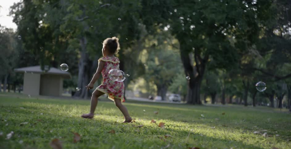 A young girl playing with bubbles in a park