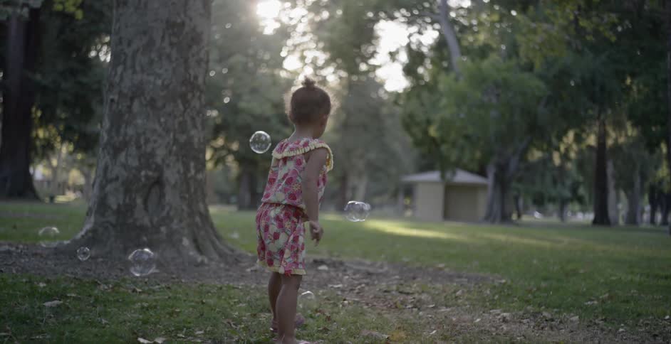 A girl in the park playing with bubbles
