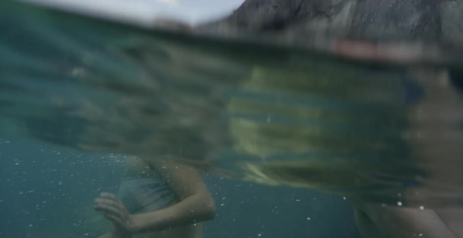 Couple wade in ocean near cliff