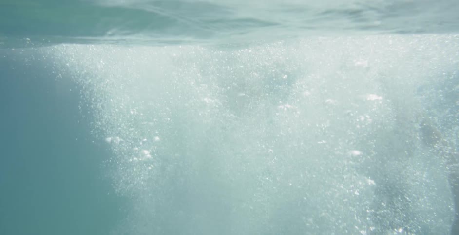 Woman and man dives into the water and make foam on a sunny day
