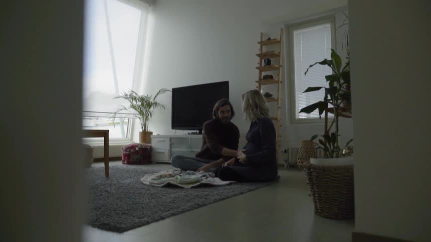Two people sit on the floor in their living room