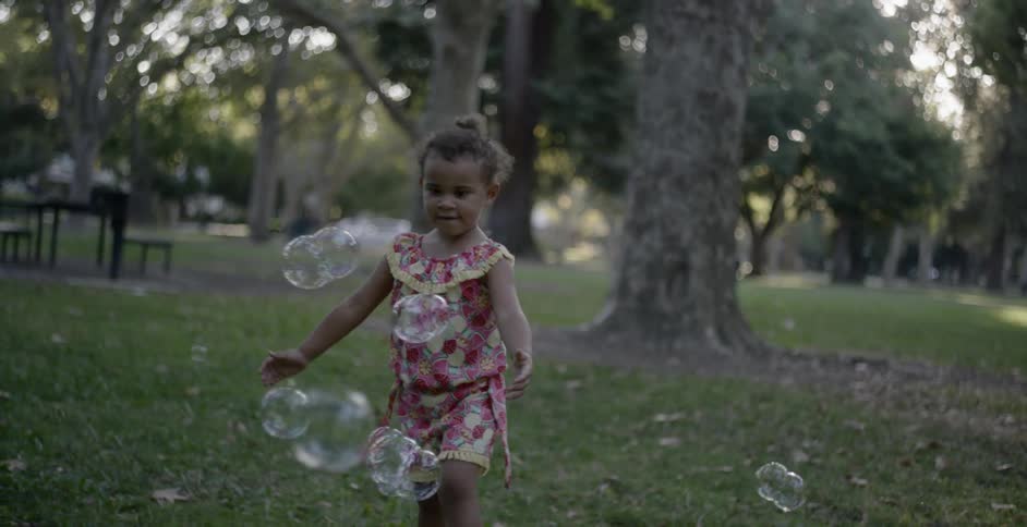 A little girl runs and chases bubbles