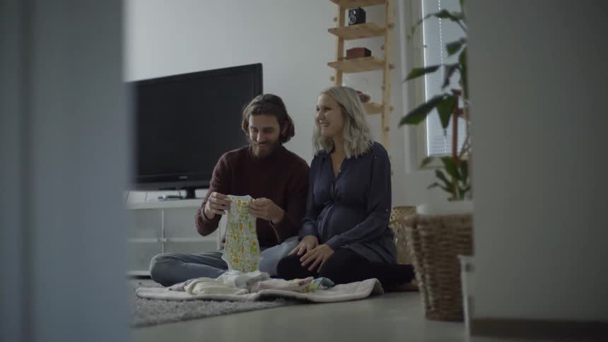 Expectant parents fold baby clothes