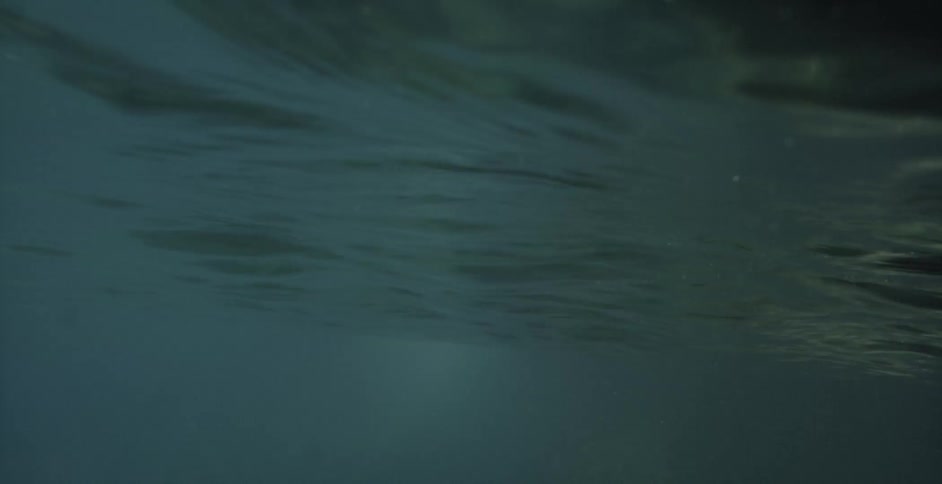 A man and a woman diving from a rocky cliff into the water below