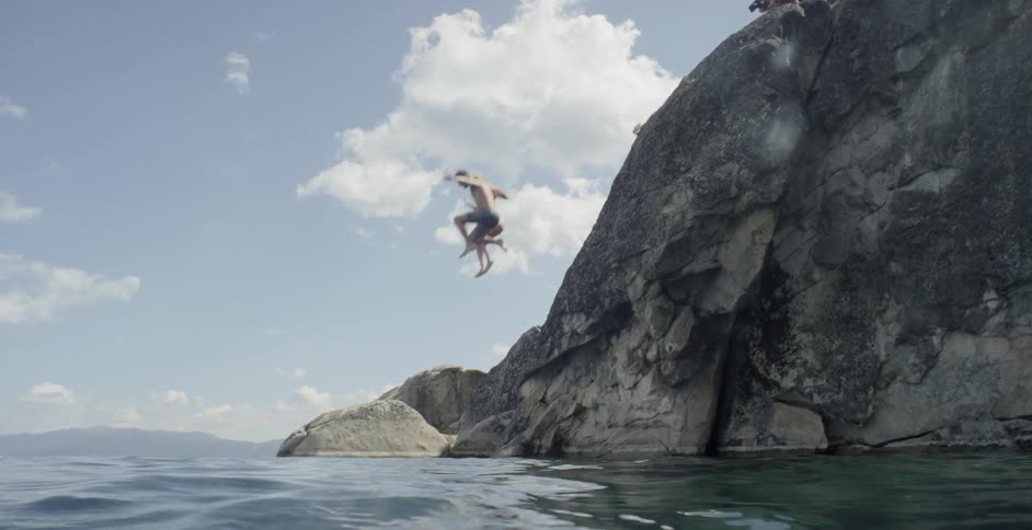 A man and a woman diving in the ocean from a cliff