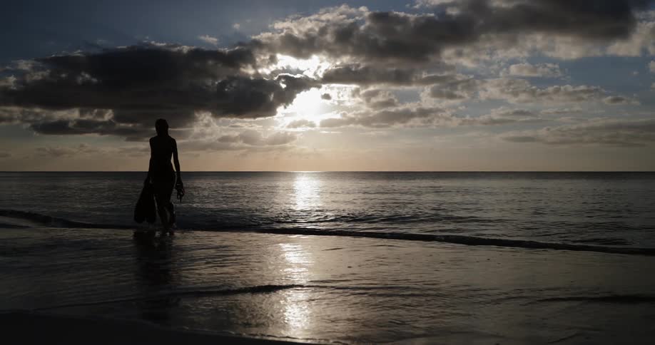 A woman walks out of the ocean and onto the beach