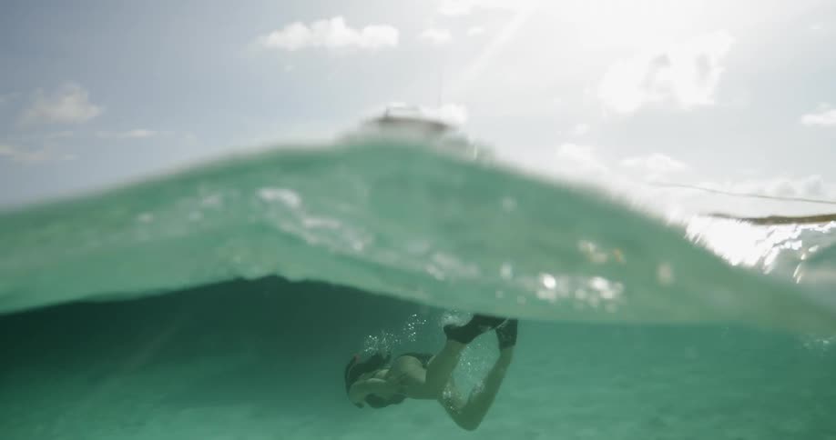 A white female caucasian is swimming underwater near a boat