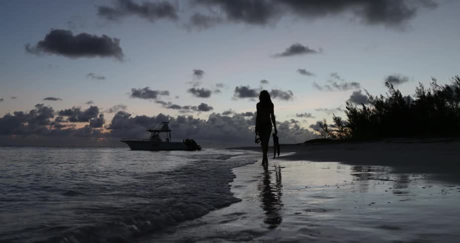 A woman walking on the beach with snorkel and flippers in hand