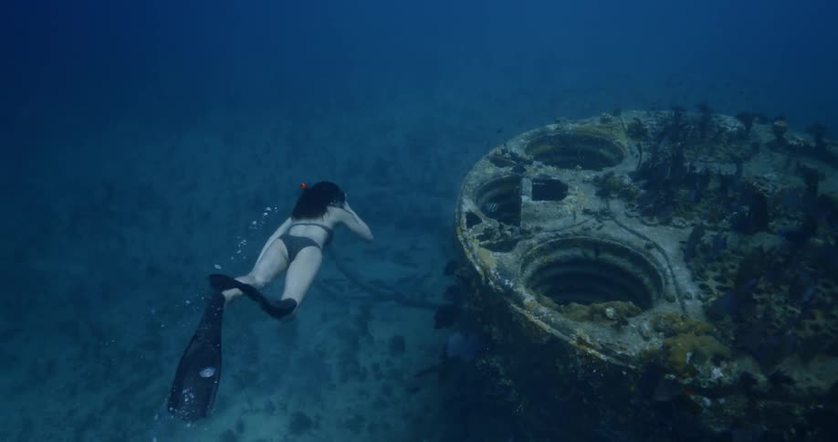 A woman snorkels and looks at fish