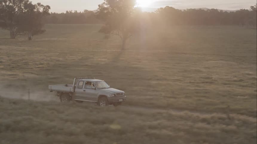 A truck traveling through the countryside on a dirt road