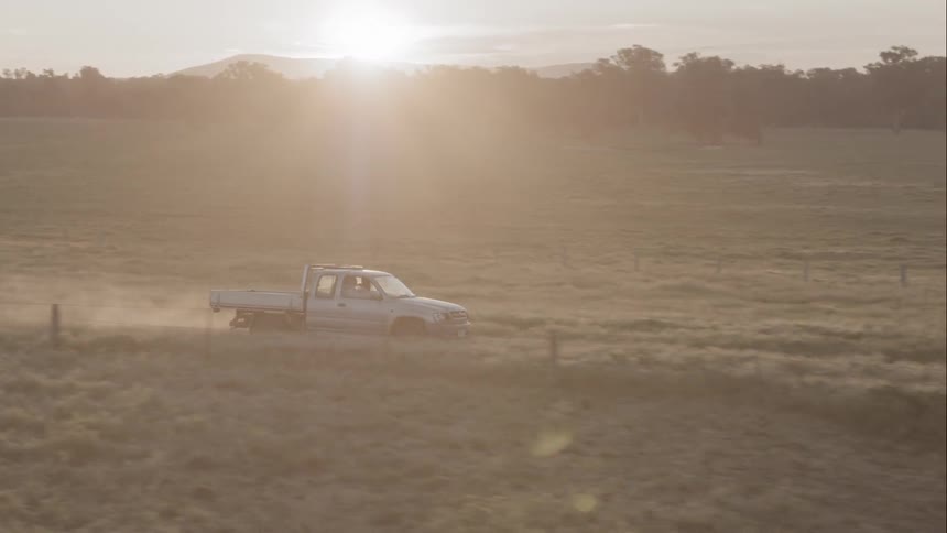 A truck drives down a dirt road out in the country