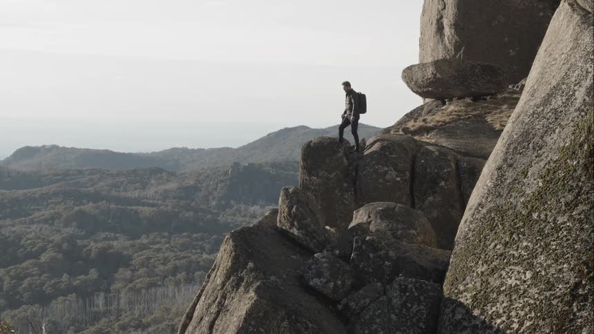 A person hiking on large rocks on a cliffside